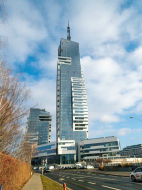 Rzeszow Polonya - 19 Aralık 2025: Modern bir gökdelen, parlak cam cephe ve ticari kullanım için ideal çağdaş mimari tasarımı sergileyen mavi bir gökyüzüne karşı duruyor.