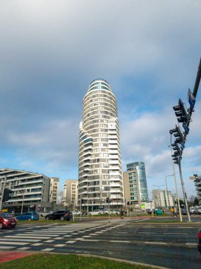 Rzeszow Polonya - 19 Aralık 2025: Çeşitli dükkanlarla çevrili uzun silindirik bir konut binası ve kentsel bir ortamda karışık kullanımlı gelişim içeren modern kentsel mimari.