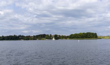 Mikolajki Polonya - 29 Eylül 2024: Bereketli yeşilliklerle çevrili sakin bir göl manzarası ve dinlenmek için ideal sakin bir atmosfer.