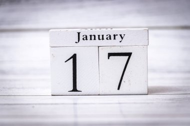 17 Ocak, eski ahşap bir takvim bloğunda kırsal bir arka planda sergileniyor. Bu resim, planlama olayları veya kişisel kilometre taşları için tarihlerin önemini vurgular.
