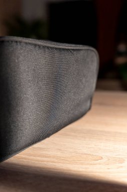 Ahşap bir yüzey üzerinde duran parlak siyah bir çantanın yakından görüntüsü desen ve tasarımını sergiliyor. Ürün tanıtımı veya sanatsal sunumlar için ideal.