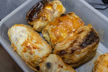 Lezzetli fırında lahana ruloları plastik bir kabın içinde altın-kahverengi bir dış görünüşü sergiliyor. Mutfak sunumları için ideal yemek blogları ya da yemek planlama fikirleri.