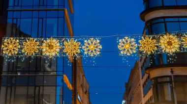 Wroclaw 'da bir kış akşamı aydınlatılmış güzel kar tanesi süslemeleri. Işıklar, tatil kutlamaları ve şehir ortamlarındaki etkinlikler için mükemmel bir ortam yaratıyor..