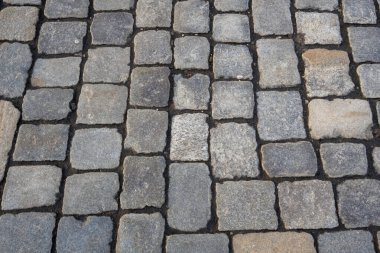 Şehir ortamları için dayanıklı bir yüzey oluşturan gri tonlarında desenli taşların yer aldığı kaldırım taşlarının yakın görüntüsü. Mimari ve tasarım projeleri için ideal.