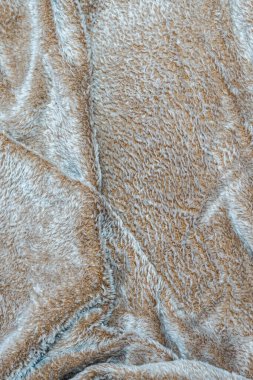 Açık kahverengi ve gri renklerin bir karışımı ile yumuşak kabarık kumaş dokusu. Ev dekorunda veya moda bağlamında arka plan tekstil ve rahat atmosfer için ideal.