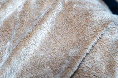 Yumuşak bej battaniye dokusunun yakın çekimi yumuşak dalgalı yumuşak kumaş sergiliyor. Ev dekorasyonu veya tekstil tasarımları için ideal.