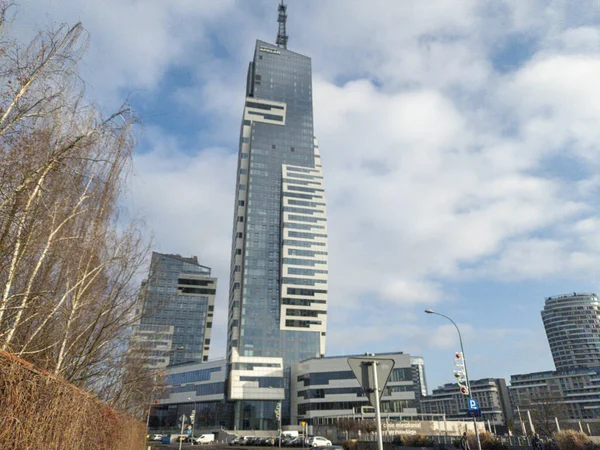 Rzeszow Polonya - 19 Aralık 2025: Modern bir gökdelen dağınık bulutlu mavi bir gökyüzüne karşı duruyor. Mimaride kentsel gelişimi sembolize eden ince çizgiler ve cam cepheler yer alıyor..