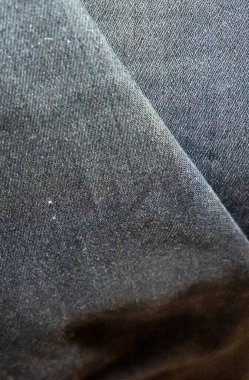 Koyu renk kot kumaşın yakın plan görüntüsü, kumaş ve yapı sergiliyor. Giyim tasarımı moda ticareti veya tekstil endüstrisi uygulamaları için ideal.
