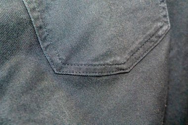 Moda odaklı kavramlar ve tekstil gösterileri için şık bir zemin sağlayan cep detayı olan siyah bir kumaşın yakın çekimi. Kıyafet reklamları veya tasarım ilhamı için mükemmel..