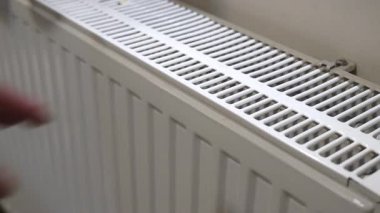 Erkek el radyatöre dokunarak ısıyı ve ısıtma performansını ölçüyor.