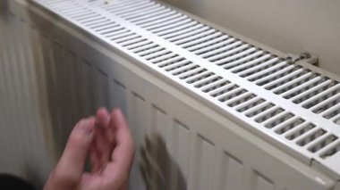 Erkek el, kışın ısıtıcı ızgarasının yanında avuç içini tutarak radyatör ısısını kontrol ediyor.