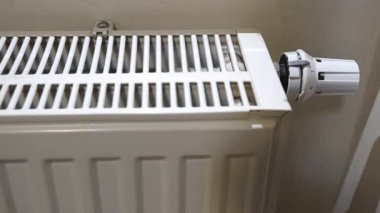 Kışın ısıtma mevsiminde ısıtıcı yüzeyine dokunarak radyatör ısısını kontrol eden adam.