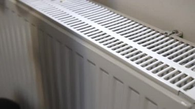 Soğuk kış boyunca sıcak kaloriferin üzerine elini koyan bir adam.