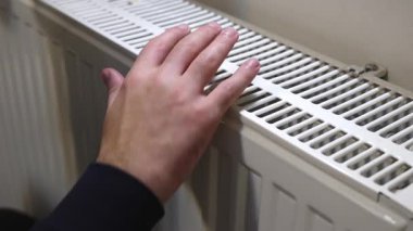 Erkek el radyatör ızgarasında dinleniyor. İçerideki ısıtma odasını kontrol ediyor.