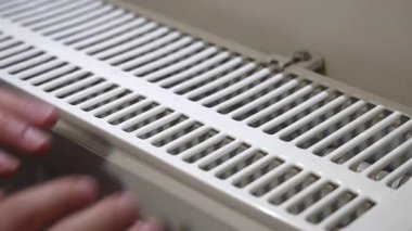 İki elini de soguk mevsimde kaloriferde ısıtan bir adam.