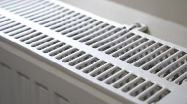 Radyatör ızgarasında dinlenen erkek el ısıtma odasındaki ısı seviyesini kontrol ediyor.