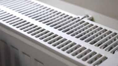 Soğuk kış boyunca elini radyatörde ısıtan bir adam.