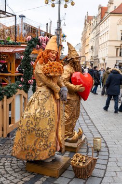 Wroclaw Polonya - 3 Ocak 2026: Altın kostümlü sokak göstericileri, canlı bir ortamda sanatçılık ve yaratıcılık sergileyen bir festival pazarında gezginleri eğlendirdiler.
