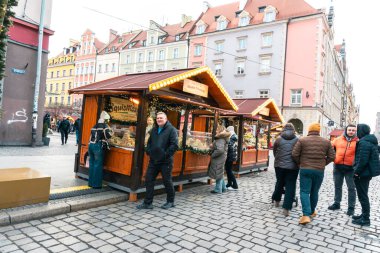 Wroclaw Polonya - 3 Ocak 2026: Wroclaw 'da canlı kış pazarı, ahşap tezgahlar, festival ışıkları ve kalabalık caddelerde yerel ikramlar sunan müşteriler.