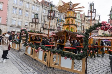 Wroclaw Polonya - 3 Ocak 2026: İnsanların ışık ve süslemelerle süslenmiş festival alışveriş ve dekorasyonlarından keyif aldığı canlı bir Noel piyasa sahnesi.