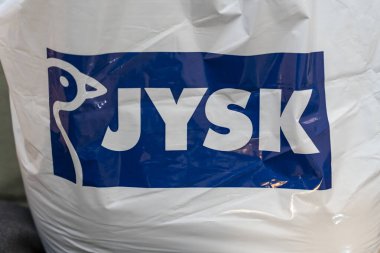 Polonya - Şubat 12026: Özel mavi logolu bir JYSK alışveriş çantasının beyaz arka planının yakından görüntüsü. Ev mobilyalarını ve perakende satış deneyimlerini temsil eder.