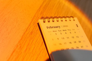 Spiral takvim Şubat 2026 'ya kadar açık. Günleri ve tarihleri gösteriyor. Ilık ışıkta yakalanarak planlama ve organizasyon için rahat bir atmosfer sağlıyor..