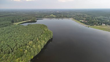 Bereketli yeşil ormanlarla çevrili sakin bir göl manzarası huzurlu bir manzara sergiliyor. Sakin sular rahatlama ve macera temalarına uygun doğal güzelliği yansıtır..