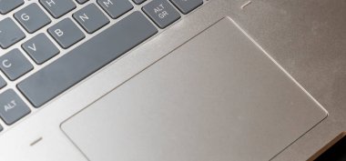 Dokunmatik ped ve klavye içeren parlak metalik bir dizüstü bilgisayarın yakın görüntüsü. Uzaktan kumandalı teknoloji veya modern yaşam tarzı kavramlarını sergilemek için ideal.