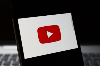 Varşova Polonya - 24 Şubat 2026: Modern iletişim ve dijital medya eğilimlerini sembolize eden karanlık bir arkaplan ile YouTube logosunu gösteren bir akıllı telefonun yakın çekimi.