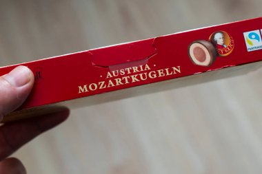 Varşova Polonya - 26 Şubat 2026: Bir kutu Mozartkugeln şekerini tutan bir elin yakından görüntüsü Avusturya markası ve Fairtrade logosu ile etiketi belirgin bir şekilde gösteriyor.