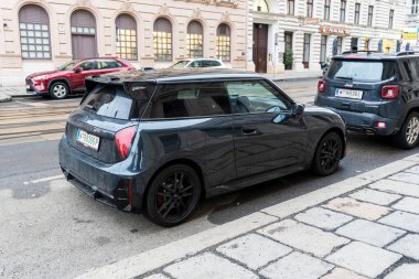 Viyana - 21 Şubat 2026: Tarihi bir cadde boyunca park edilmiş siyah bir kompakt araba klasik mimariye karşı modern tasarımı otomotiv pazarlaması ve kentsel yaşam tarzı temalarına karşı sergiliyor.