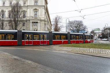 Viyana - 21 Şubat 2026: Şehir caddesinde virajda ilerleyen modern bir tramvay. Arka plandaki mimari, kentsel hayat dinamiklerini geliştiren tarihi zarafeti yansıtıyor..