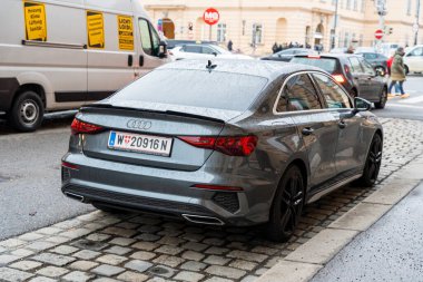 Viyana - 21 Şubat 2026: Islak bir caddeye park etmiş gri bir Audi sedan yağmurlu bir günde şehrin kentsel atmosferini yakalıyor.