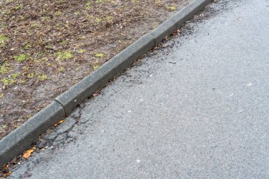 Şehir ve doğal ortamlar arasındaki zıtlığı gösteren bir yol boyunca beton kaldırım ve düz olmayan bir çakıl yolunun yakın görüntüsü. Kentsel planlama bağlamları için ideal.