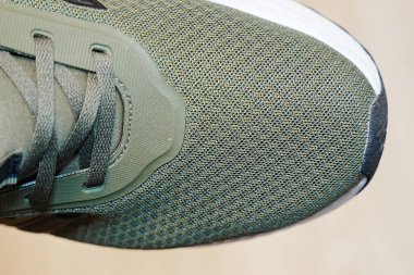 Yeşil atletik ayakkabı sergilenen yakından görüntü karmaşık ağ dokusu ve bağcıklar. Spor fitness ve yaşam tarzı markalaşması için uygun konfor ve stili vurguluyor.