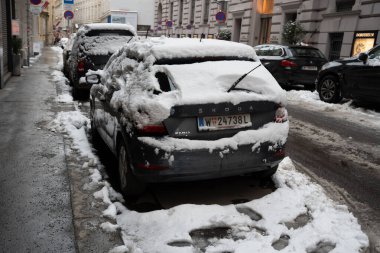 Viyana - 21 Şubat 2026: Şehir caddesinde yoğun karla kaplı gri bir Skoda arabası. Sahne, kar kaplı araçlar ve şehir mimarisi ile kış koşullarını yakalıyor..
