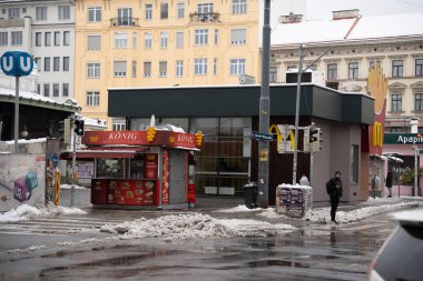 Viyana - 21 Şubat 2026: Konig adlı bir gıda tezgahının yer aldığı sokak sahnesi McDonalds mağazası ve karla kaplı sokaklar kentsel yaşamı ve kış havasını gösteriyor.