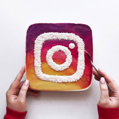 Meyve, böğürtlen ve hindistan cevizli meyve suyu kasesi. Eller, beyaz plaka, beyaz arka plan. Instagram yaratıcı logosu. Renkli 