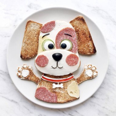 Krem peynirli tost ve mırıldanma. Çocuklar için güzel bir kahvaltı. Güzel köpek yavrusu şeklinde nefis yemek sanatı. Beyaz plaka ve beyaz arkaplan.