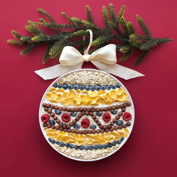 Noel zamanı, Noel ağacı, kırmızı arka plan, mısır gevreği, süt, meyve, böğürtlen, ahududu, yabanmersini, beyaz tabak. Noel süsü. Yaratıcı fikir, reklam, kahvaltı..