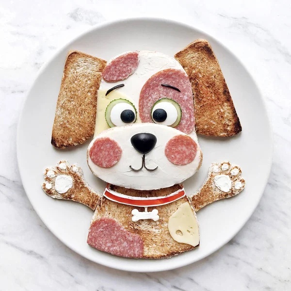 Krem peynirli tost ve mırıldanma. Çocuklar için güzel bir kahvaltı. Güzel köpek yavrusu şeklinde nefis yemek sanatı. Beyaz plaka ve beyaz arkaplan.