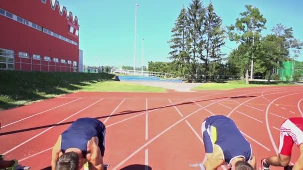 Cuatro atletas corriendo fuera de los bloques de partida — Vídeo de stock