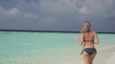 Plajda koşan bikinili kadın.