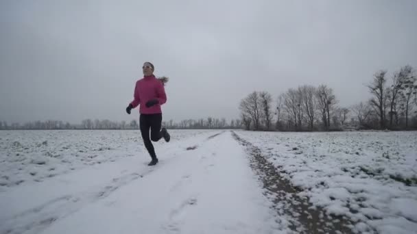 Woman running on snowy road — Stock Video