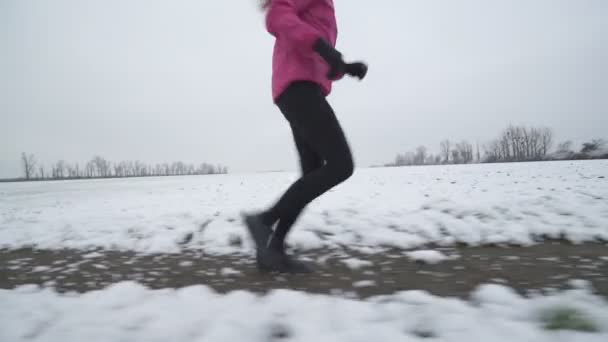 Woman running on snowy road — Stock Video