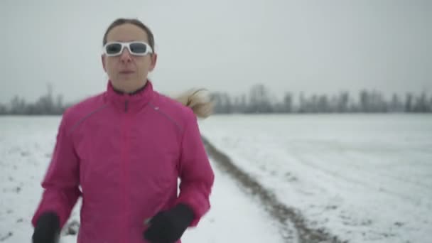 Femme courant sur une route enneigée — Video