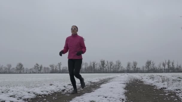 Mujer corriendo en el camino nevado — Vídeos de Stock