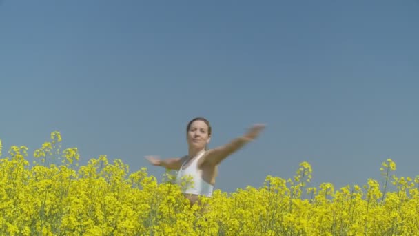 Happy woman turning in rape field — Stock Video