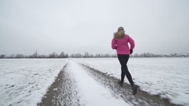 Женщина бежит по снежной дороге — стоковое видео
