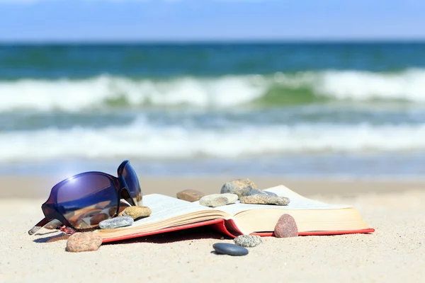 Libro y gafas de sol en la playa — Foto de Stock
